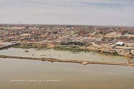 Image du Maroc Professionnelle de  Cette vue aérienne de la ville de Laayoune nous découvre au premier plan le fleuve la Sakia Al Hamra juste derrière protégé par une digue la partie stagnante des égouts à ciel ouvert, malgré tous les investissements la ville manque cruellement d'une station de pompage et d'une station de traitement des eaux usées, le 9 Avril 2010. (Photo / Abdeljalil Bounhar) 